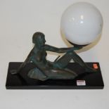 An Art Deco style resin table lamp in the form of a semi-nude dancer supporting a globular glass