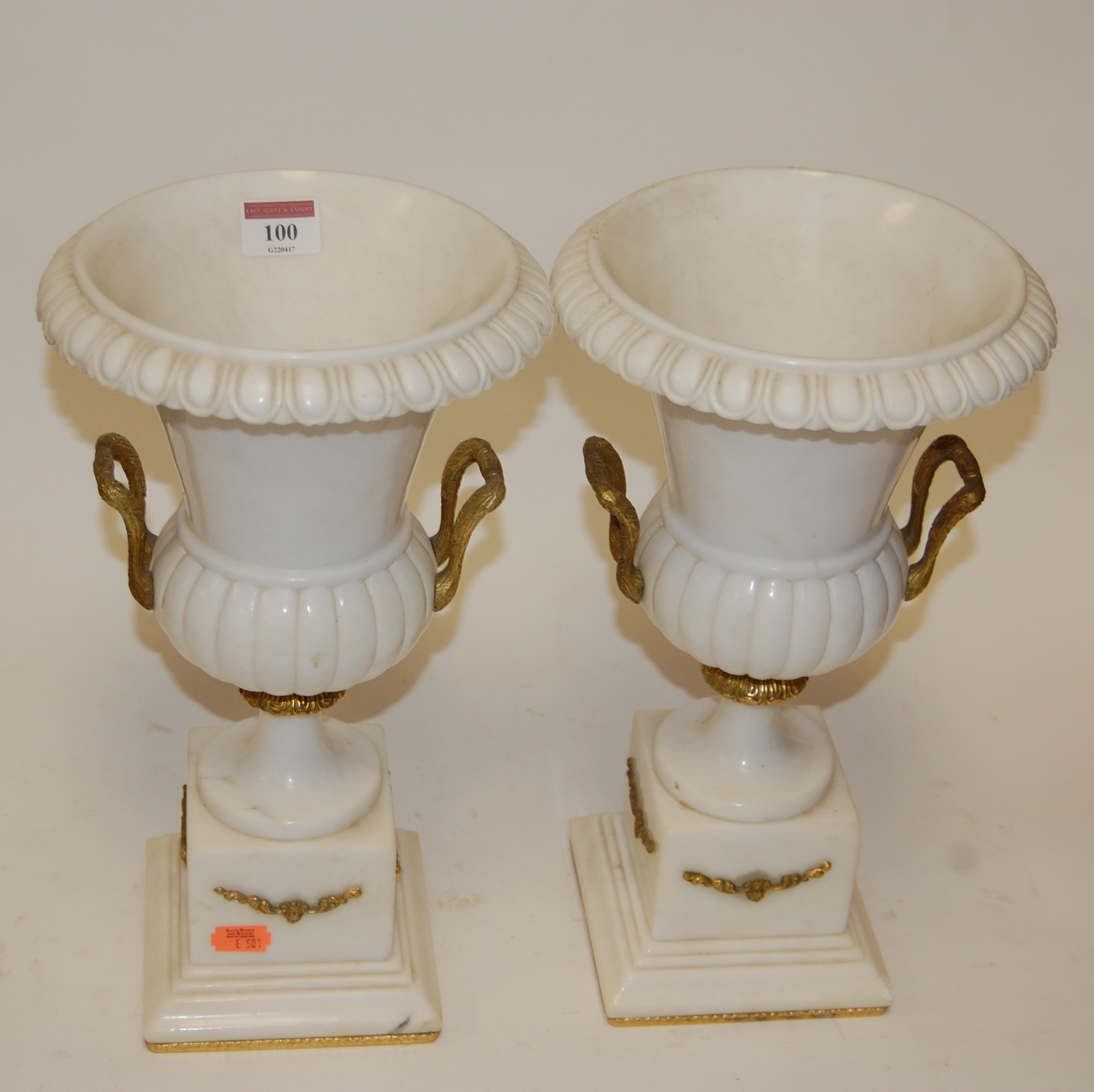 A pair of faux marble table lamps each in the form of a campagna shaped urn with gilt metal mounts