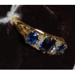 An 18ct gold, sapphire and diamond ring, arranged as three graduated oval cut sapphires,