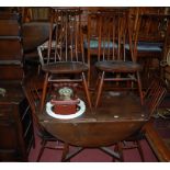 An Ercol dark elm dining suite comprising dropflap table, set of four stickback chairs,