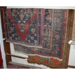 A Turkish red ground woollen rug; together with a Persian blue ground woollen rug;