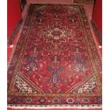 A Persian woollen red ground rug, having all-over geometric stylised decoration,