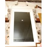 A white painted architectural wall mirror with applied carvings,