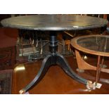 An ebonised and gilt tooled leather inset circular pedestal table, dia.