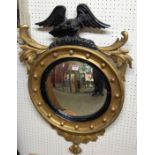 A late 19th century gilt wood convex wall mirror with eagle pediment,