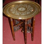 An Eastern circular brass topped folding Benares table