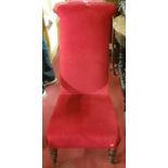 A Victorian walnut framed and red upholstered prie-dieu, raised on turned forelegs,