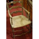 A pair of circa 1900 French provincial oak rushseat ladderback elbow chairs;