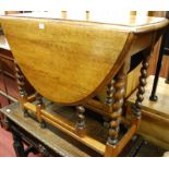 An early 20th century oak barley twist drop leaf dining table, having a gate leg action,