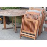 A modern teak circular patio table together with six folding chairs