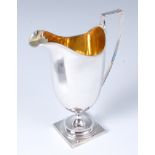 An Edwardian silver pedestal cream jug, of helmet form, having gilt washed interior,