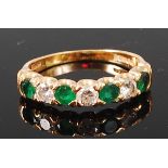 A modern 18ct gold, emerald and diamond set half eternity ring,