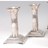 A pair of late Victorian silver Corinthian column candlesticks, having beaded detachable sconces,