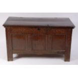 A circa 1700 joined oak three panel coffer, having loop hinges above rosette carved frieze,