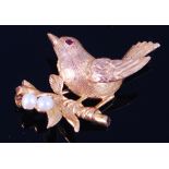 A modern 9ct gold brooch, modelled as a robin upon a branch, having ruby set eye,