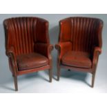 A pair of brown leather upholstered barrel back armchairs, in the George III style,