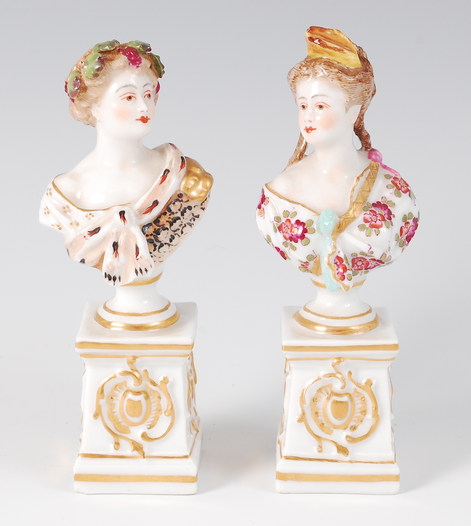 A pair of Meissen Dresden bust figures, each of maidens in the 18th century style,
