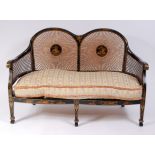 An early 20th century black Japan lacquered settee, having split cane back and sides,