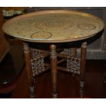 An Eastern engraved brass topped folding Benares table