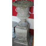 A reconstituted stone campagna garden urn, raised on square pedestal base, h.