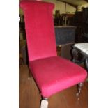 A Victorian walnut framed and red upholstered prie-dieu, raised on turned forelegs,