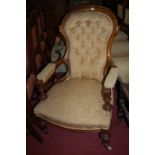 A mid-Victorian walnut framed and yellow floral buttonback upholstered spoonback armchair