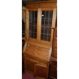 An early 20th century geometric moulded oak bureau bookcase having twin door lead glazed upper