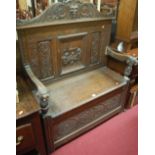 An early 20th century low relief carved oak two seater box seat settle (with damage to one arm),