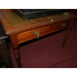 An Edwardian walnut and gilt tooled leather two drawer writing table raised on turned and reeded