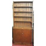 A stained pine bookcase cupboard, the open shelves over twin recessed panel cupboard doors,