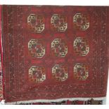 A Persian woollen red ground Bokhara rug;