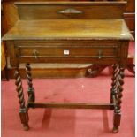 An early 20th century moulded oak ledgeback single drawer side table raised on barley twist turned