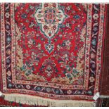 A Persian woollen red ground rug;