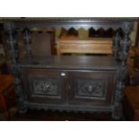 A late 19th century heavily carved ebonised oak buffet, having twin Green Man mask carved doors,