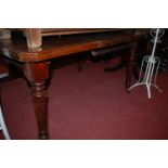 An Edwardian walnut extending dining table, having wind-out action and single extra drop-in leaf,