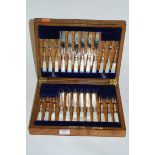 An early 20th century oak cased 12 place setting of silver plated tea knives and forks each with