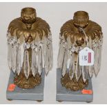 A pair of gilt metal table candlesticks, each with glass prism drops on marble plinth base,