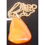 A butterscotch amber pendant of polished natural form on 15ct gold rope twist neck chain,