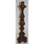 A carved wooden altar stick in the baroque style having carved acanthus leaf decoration and traces