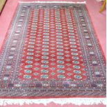 A Persian woollen Bokhara rug having four rows of medallions on a red ground within multiple