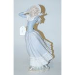 A large Lladro figure of a girl in standing pose with hat and scarf,