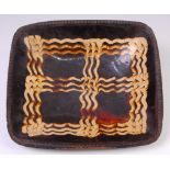 A late 18th century slipware baking dish, of rectangular form, decorated in brown and ochre, w.35.