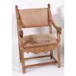 A 19th century carved limed oak elbow chair, in the 17th century style, having padback and seat,