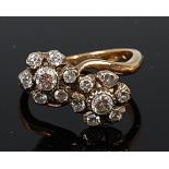 An 18ct gold diamond crossover ring arranged as twin flower head settings,