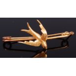 A 15ct gold safety pin brooch surmounted with a bird in flight, 3.7g, 4.