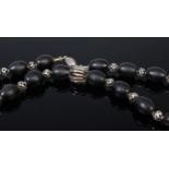 A beaded black glass necklace having pierced white metal ball dividers,