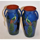 A pair of Torquay Pottery twin handled vases, each on a blue ground with applied peacock decoration,