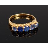 An 18ct gold sapphire five stone ring, the claw set round cut sapphires in a line setting,