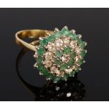 An 18ct gold, emerald and diamond set flower head cluster ring, as a five tier basket setting, 6.