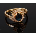 A modern 18ct gold sapphire and diamond cluster ring arranged as a four claw set oval cut sapphire